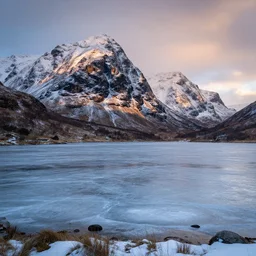 award winning landscape photography, scottish rugged mountains in winter with frozen loch, evening light
