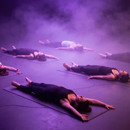 classical dancers are lying on yoga mats and connected by wires in a purple smoke