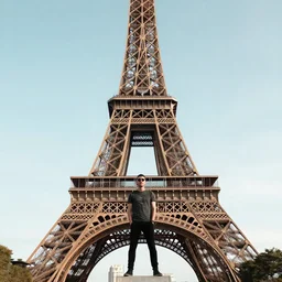 photograph of a guy standing on top of the eiffel tower, portra 8 0 0
