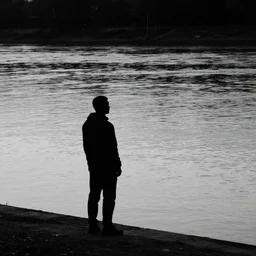 silhouette of a man standing on the banks of a river