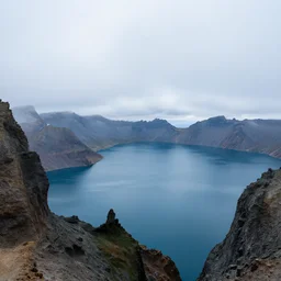 wide angle cinematic photo of a mountains landscape with a blue lake on a big mist, ultra detailed matte painting
