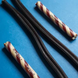 strands of black licorice on a blue background, candy, twizzlers, chesley bonestell, vincent di fate