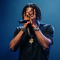 photo of the rapper chief keef with his hair covering his face, performing on stage