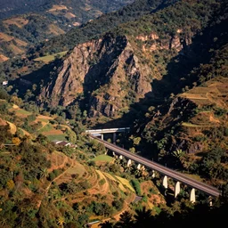 90s kodak photo of a rural countryside, hilly, sharp cliffs, forested, natural, beautiful, warm lighting, hyperdetailed, tilt shifted, highway, train bridge, digital photography