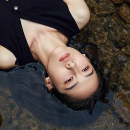 close up of face of fashion model floating in water of a stream, top view, official versace editorial, highly detailed