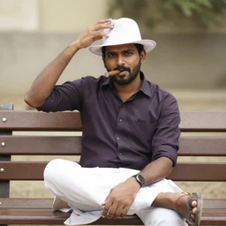 vinod striking a pose with a white hat and cigar in his mouth as he sits on his bench