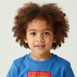 close up photo of a 1 5 yo kid with very curly hair wearing a lego t - shirt