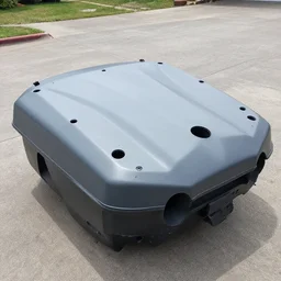 impossible smooth dented surface area big of broken machine on driveway, many unknown features sticking out of it, angular plastic top with many orifices