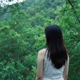 a girl looking out over a lush green forest