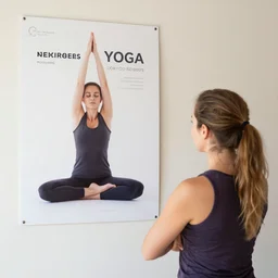a photo of a yoga teacher, looking at a yoga poster, designed by verena loewensberg