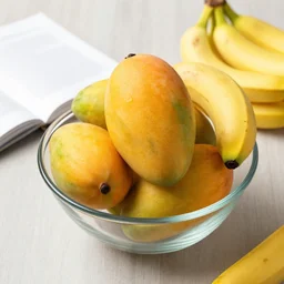 a glass bowl filled with mangos and bananas, cookbook photo