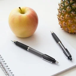 photo of an apple - pen and a pineapple - pen, on a writing - desk.