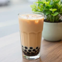 a 4 k photorealistic photo close up of a glass of boba tea on a table next to a potted plant