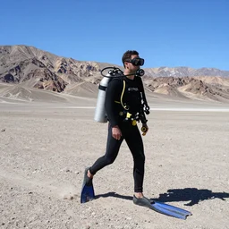 a scuba diver with fins on his feet is walking through death valley, bright sunny day, photography, highly detailed, high quality,