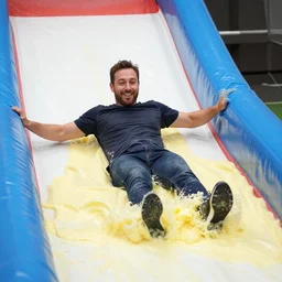 a man sliding through pudding, slip n slide, professional photo, funny