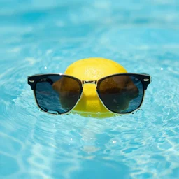 a lemon with sunglasses in a pool