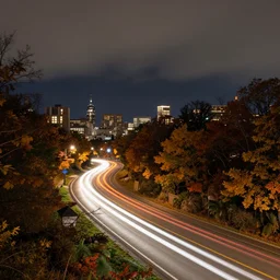 landscape photography by jake guzmann, a city at night, car lights, long exposure, autumn, dramatic lighting, beautiful