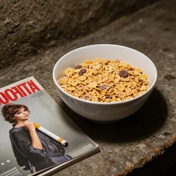 a bowl of cereal sitting next to a cigarette in a basement, cover of cosmopolitan magazine, hyperrealistic