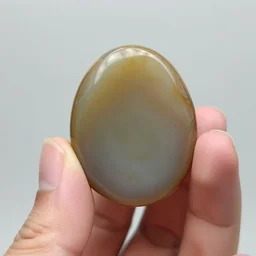 hand photography, discernible hand with thumb and four fingers, holding a moss agate