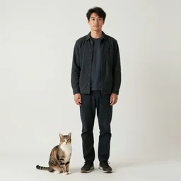 a full body portrait of a man standing. 1 meter to his left sits a cat