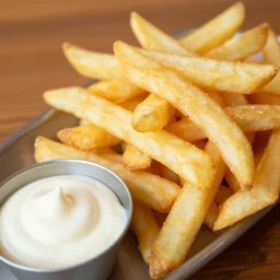 the most delicious portion of french fries with mayo on the side, on a wooden table, close - up, photography