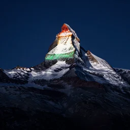 a photo at nighttime of llumination of the matterhorn in the colors of indian flag, projected illuminated on the matterhorn mountain at night