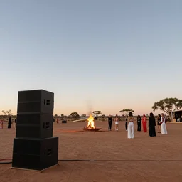 low angle shot looking up, dancefloor kismet, diverse costumes, clean composition, desert transition area, front left pa speaker stack, bonfire, night, australian desert, zaha hadid, xf iq 4, symmetry, sony a 7 r, 1 5 0 mp, 5 0 mm, f 1. 4, iso 2 0 0, 1 / 1 6 0 s, golden ratio, rule of thirds