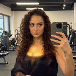 female influencer as mona lisa face in gym instagram selfie photo looking to the left with curly hair in room # photography # beauty