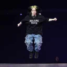 photo of billie eilish with black hair jumping onto stage