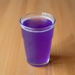 a cup of a purple liquid on a wooden table