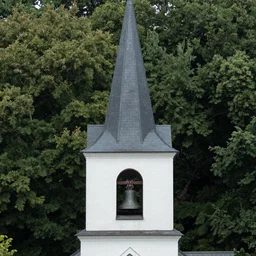 a church steeple buried up to the bell tower in an old forest