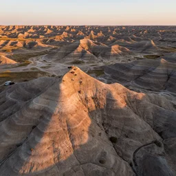 aerial overhead close up shot of a badlands fossil dig site in golden hour lighting