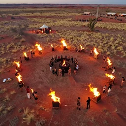aerial shot of a burning man party, in the red desert with dry grass