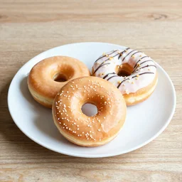 A couple of donuts on white plate on wooden table,