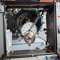 photo inside the iss, with a small torsion pendulum clock floating inside. highly - detailed, award - winning