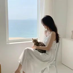 a woman in a white dress sitting on chair and a cat on her lap in a white room in vanice, there is a window to the sea