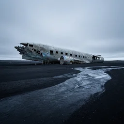 low angle cinematic of abandoned aircraft carrier in the middle of endless black sand beach in iceland, rivers