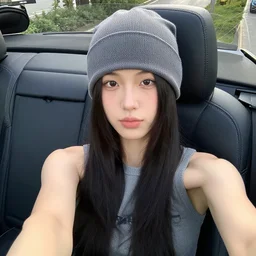 girl sitting in convertible car wearing beanie and sleeveless shirt, selfie