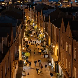 high quality photograph of a city at night, photo taken at eye height, nightlife, people walking, 4 k professional photograph, nice place to live, midrise buildings, narrow streets, soft warm street lamps, small windows, cozy, trending on artstation, detailed, beautiful, photograph, realistic