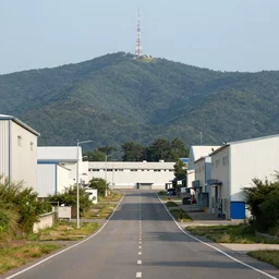 looking down road of warehouses. hills background with radio tower on top. telephoto lens compression.