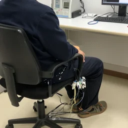 person in a chair with their head hooked up to cables and machinery, coherent