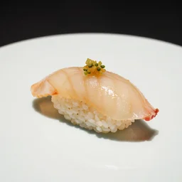 a single piece of nigiri on a white place with garnish