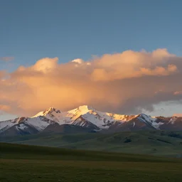 a beautiful landscape photograph, orange clouds, blue sky and green grassland, snowy mountains