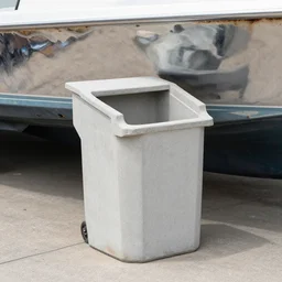 dry dock concrete clamshell grill garbage can on an abandoned shiny  chromeplated dented angular motorboat hull,