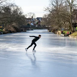 ice skater skating on a frozen river stour in canterbury, in winter