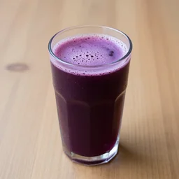 a cup of purple juice on a wooden table
