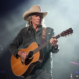 willie nelson on stage, four fingers holding a guitar. god rays through fog.