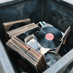 photo of the inside of a dumpster filled with broken vinyl records