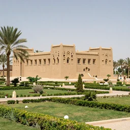 landscape photograph of a large najdi mud house palace with gardens and palm trees. Detailed