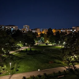a nighttime view of a city park with buildings in the background, a matte painting by zlatyu boyadzhiev, deviantart, dau - al - set, nightscape, panorama, creative commons attribution
